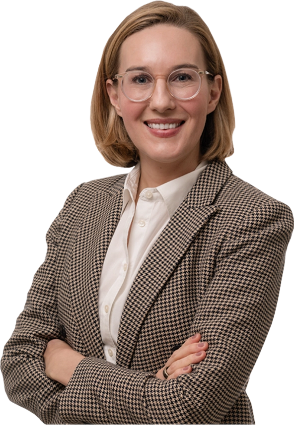 Emily Sheeren, smiling with arms crossed, wearing glasses and a houndstooth blazer
